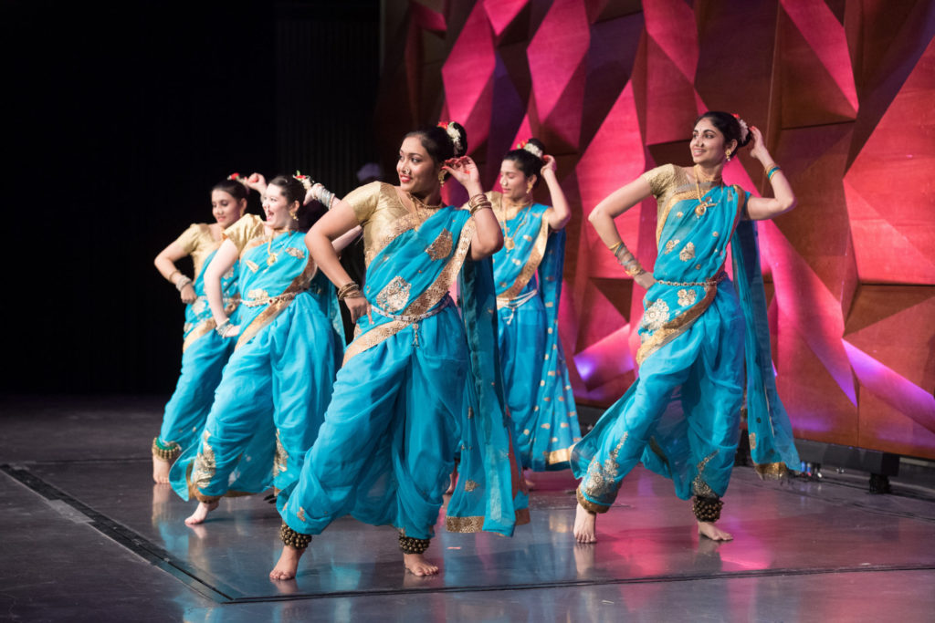 A dance troupe in blue outfits perform on stage