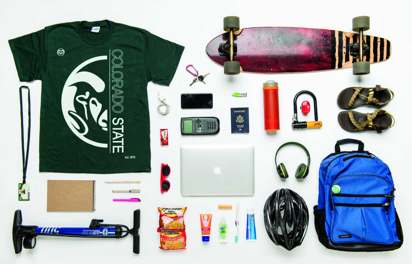A variety of items one would find in a backpack displayed on a white background. A Passport is front and center.