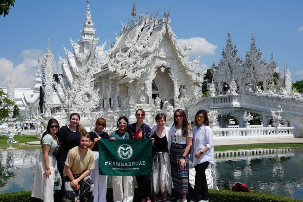 Students holding up a Rams Abroad flag in front of a temple