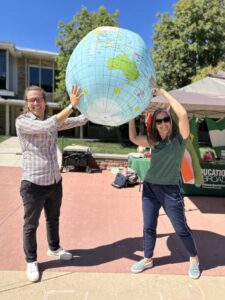 two people at the lory student center plaza hold up a giant inflatable earth