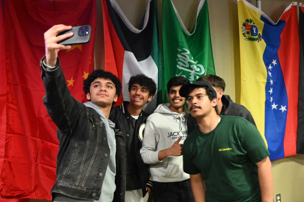 Group of students taking a selfie in front of the national flags