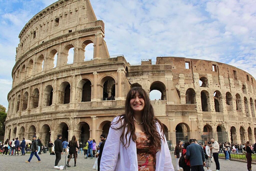 A student smiling in front of the colosseum in Rome