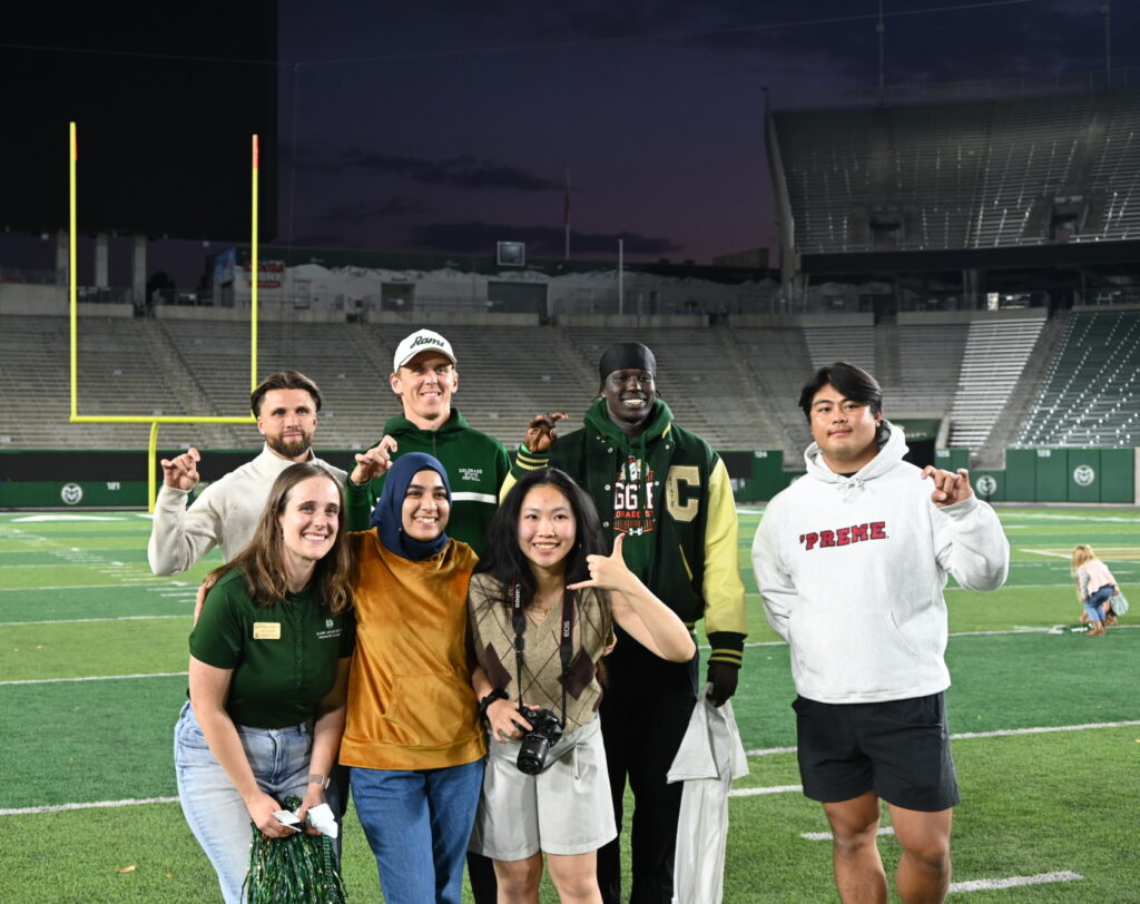 A group of international students on the Football field holding up their fingers to make rams horns