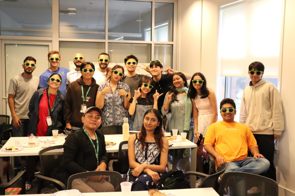 A group of students pose for a photo with various props