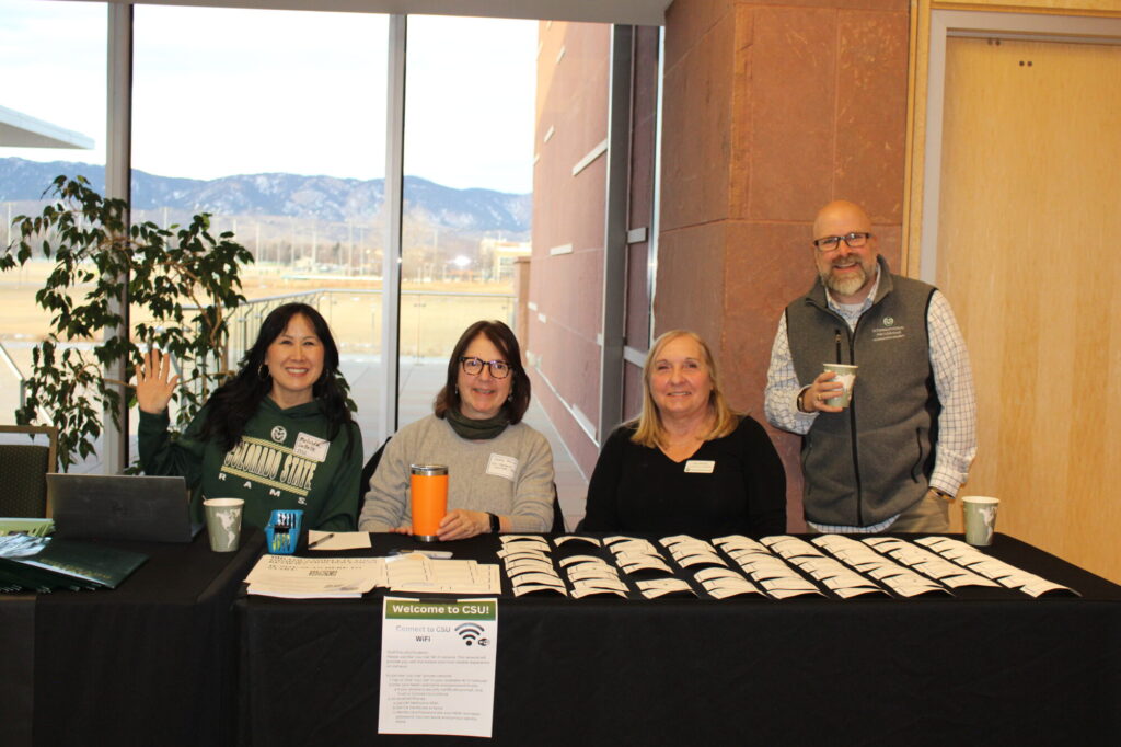 Four people smiling at a welcome desk