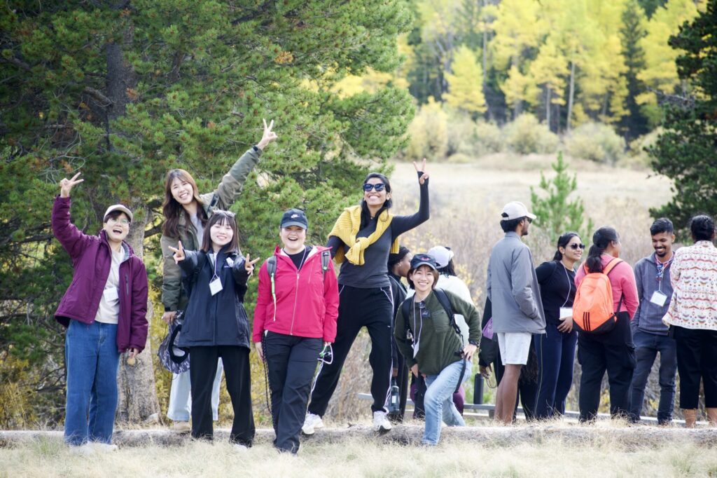 A group of students hold up the peace sign with their hands on a hike