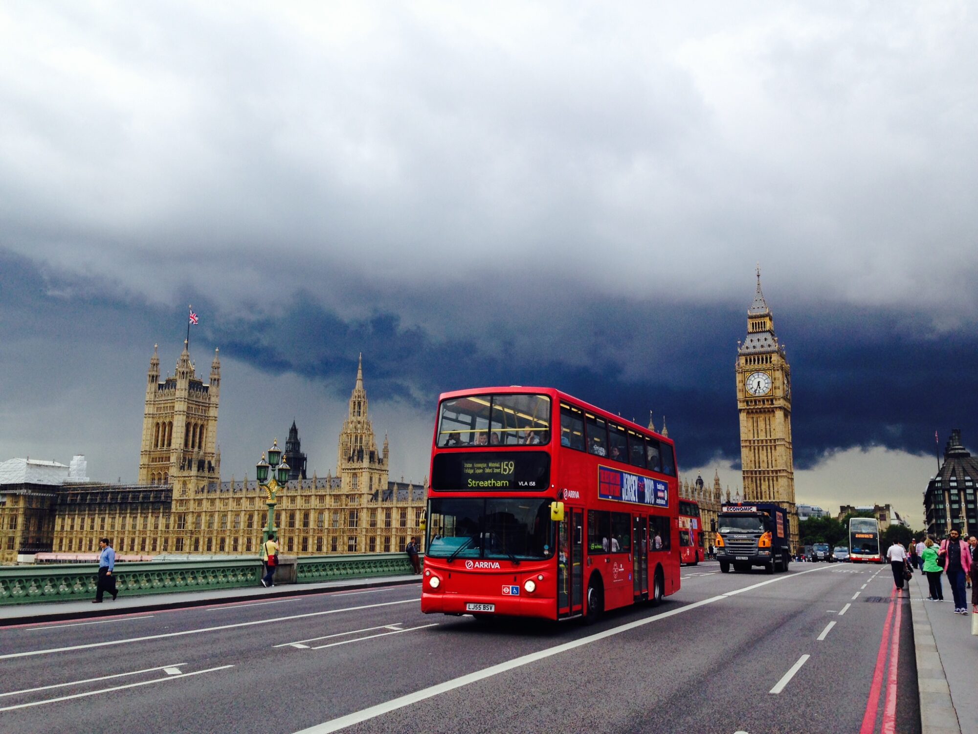 A double-decker bus drives through London with Big Ben in the background.