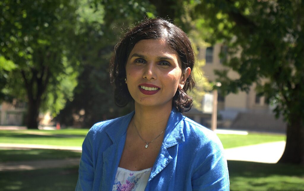 A photo of a person in front of trees on a sunny day