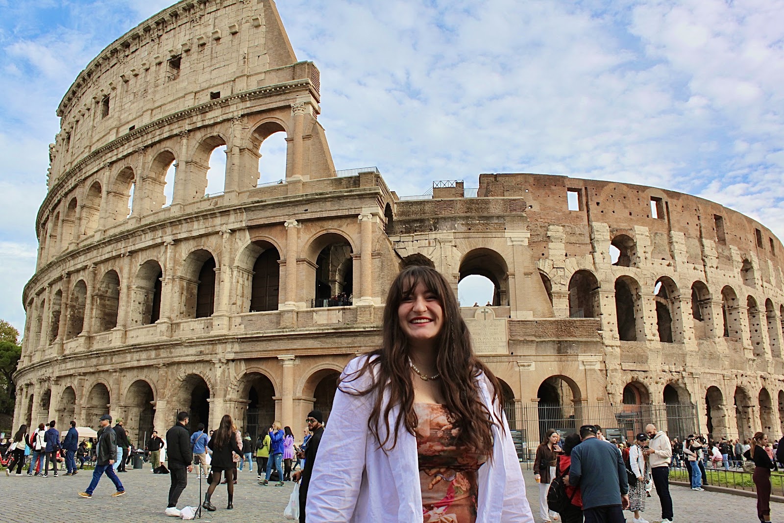 A student smiles in front of the colosseum