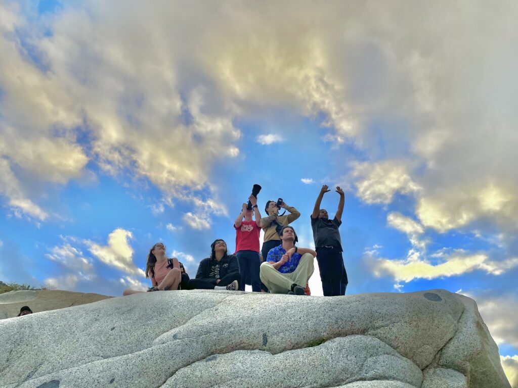 students standing on a rock looking up at the sky