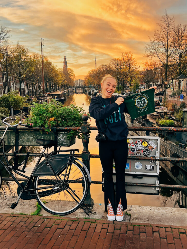 a student holding up a csu flag at a canal