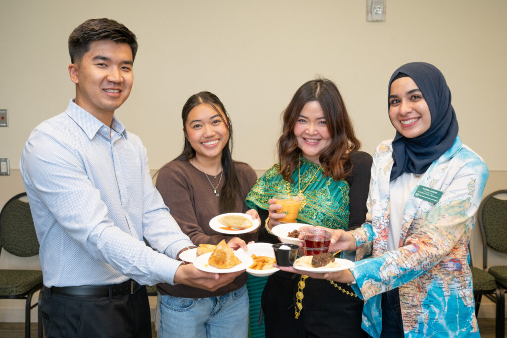 Four students holding up plates of food