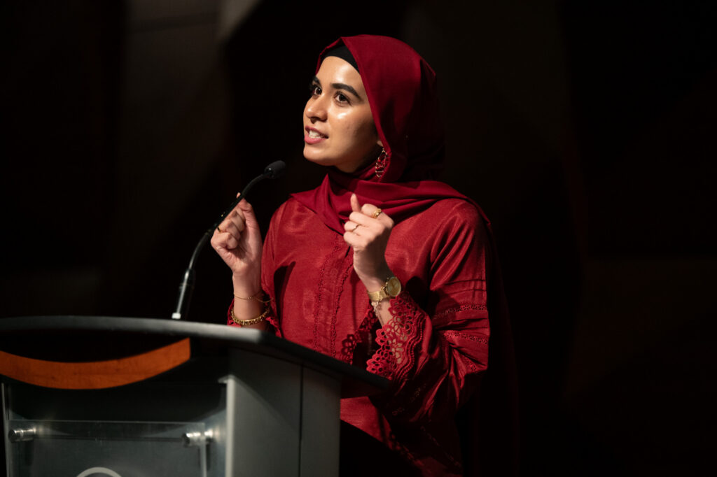 Areen Akbar speaks into a microphone at a graduation ceremony