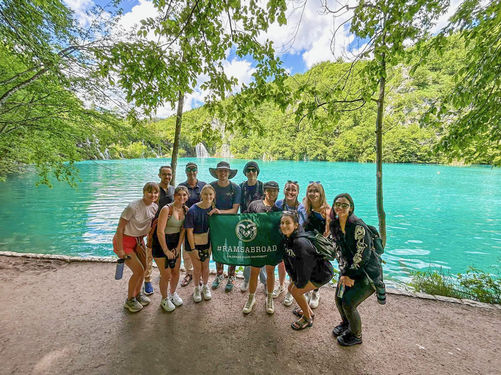 A group of students in front of a bright blue lake