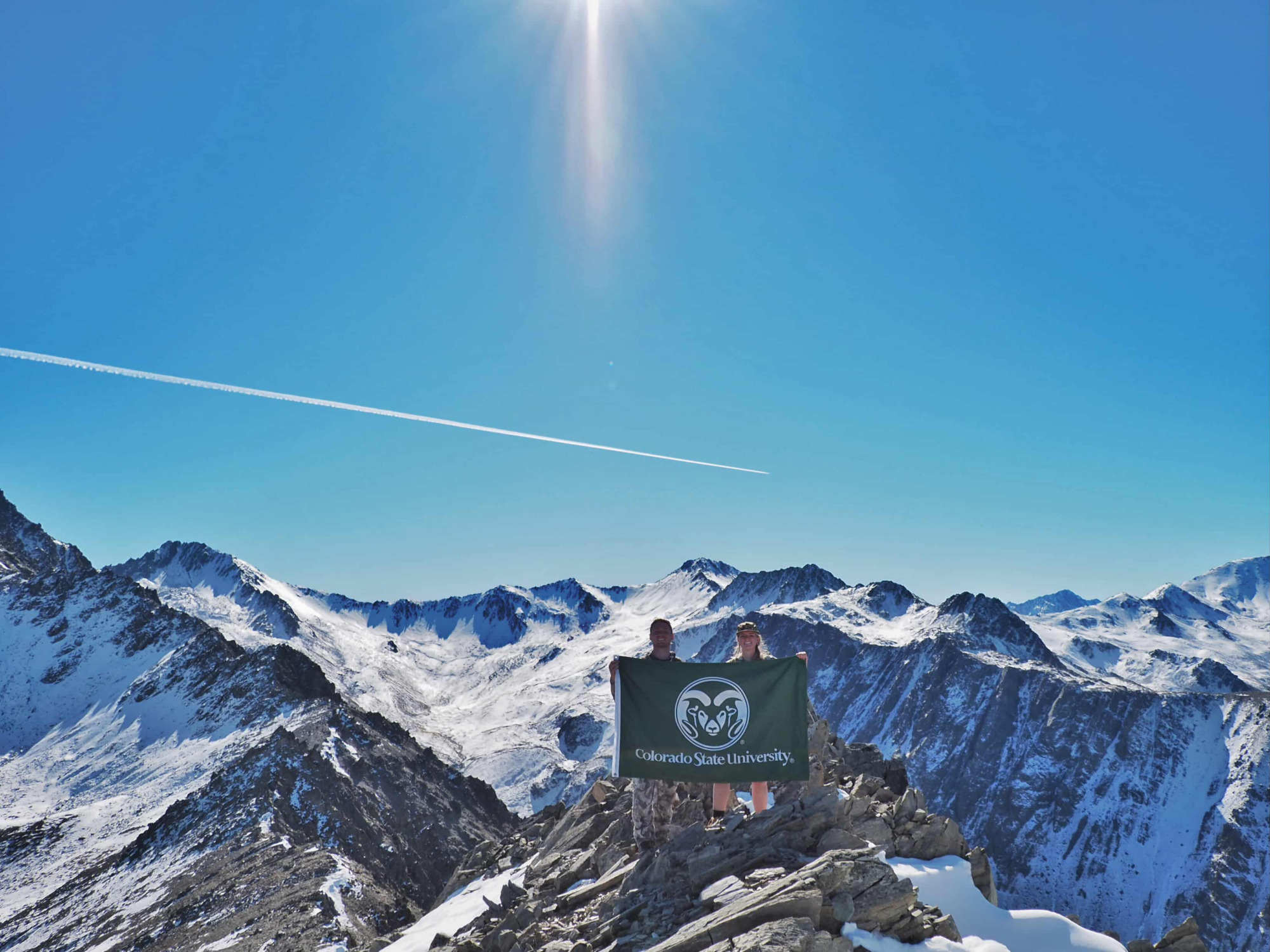 2 Students on Mountain top holding a CSU flag
