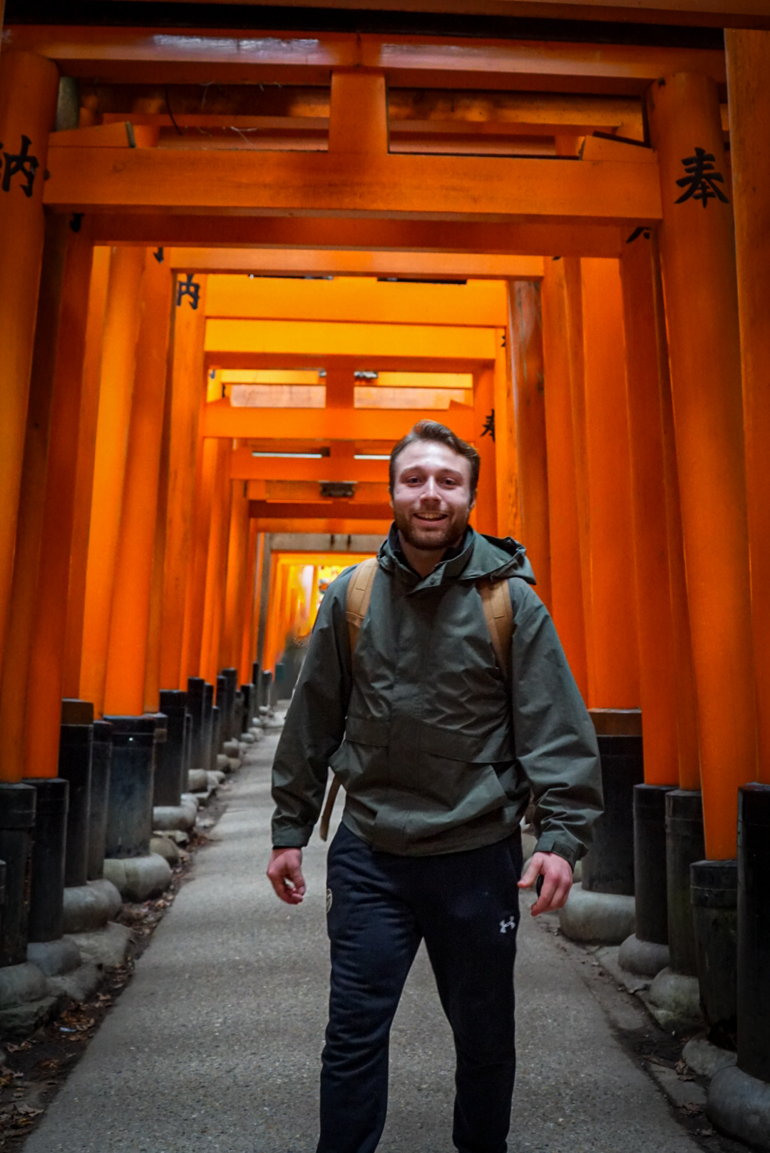 A student standing underneath red Torii Gates in Japan