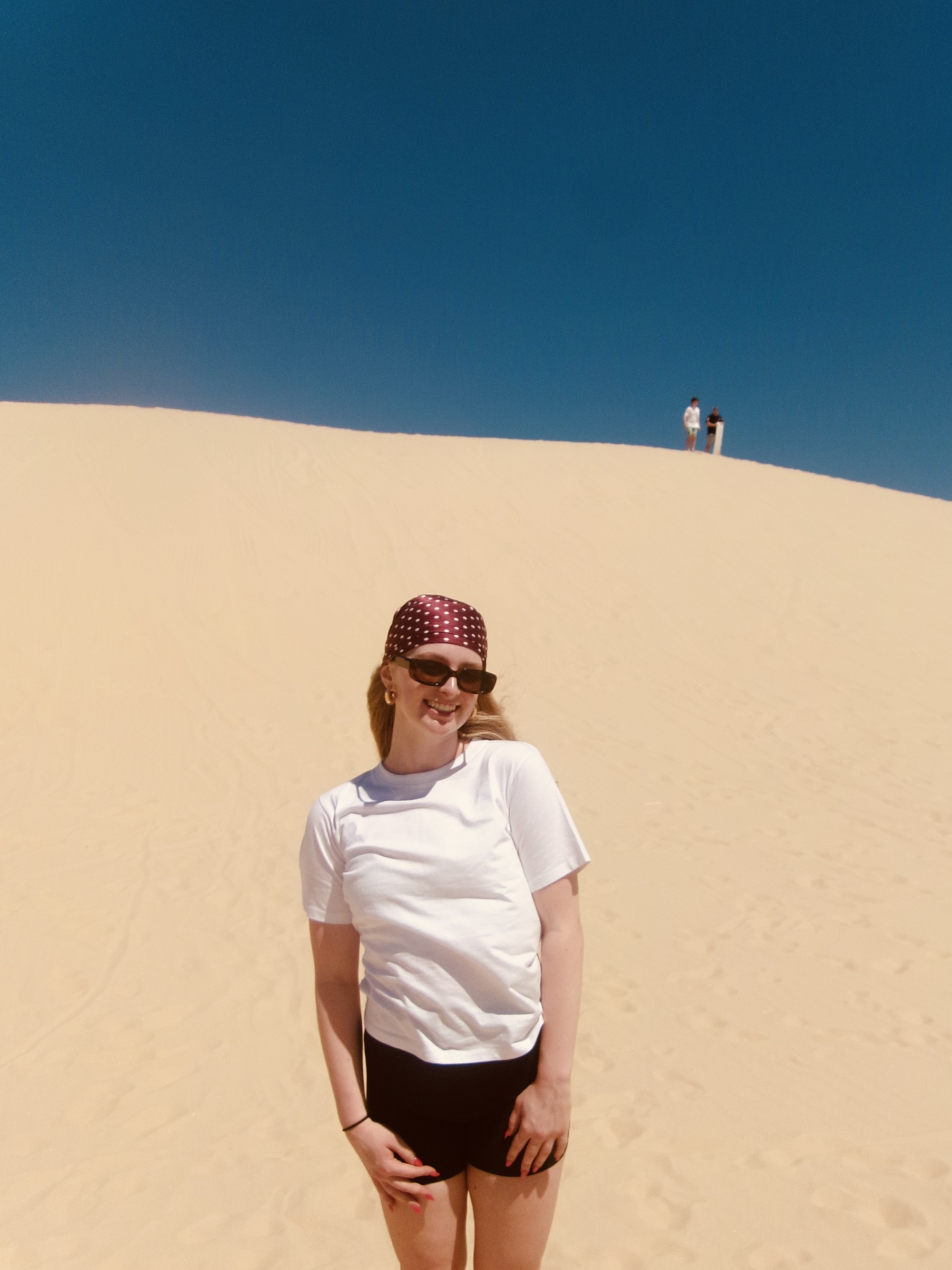 A student standing in front of a sand dune