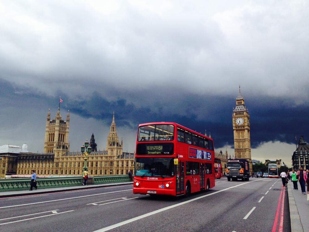 A double decker red bus driving down a london street