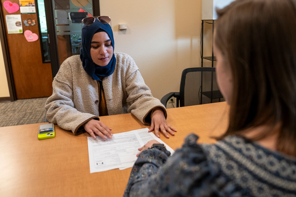 International student sits down at a desk with an advisor